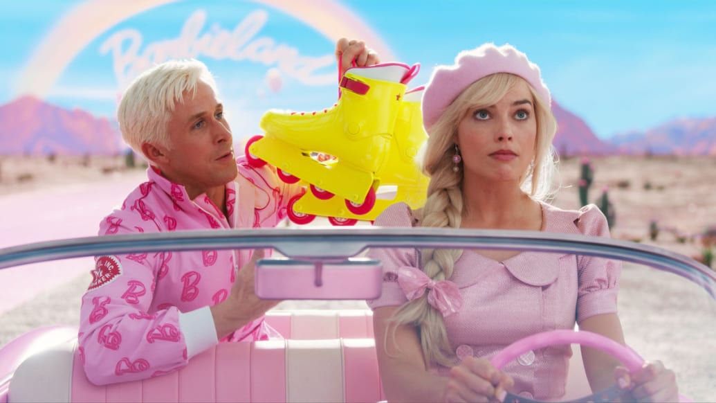 Margot Robbie como Barbie conduce un auto rosa, mientras que Ryan Gosling como Ken sostiene un par de patines amarillo neón en el asiento trasero detrás de ella.